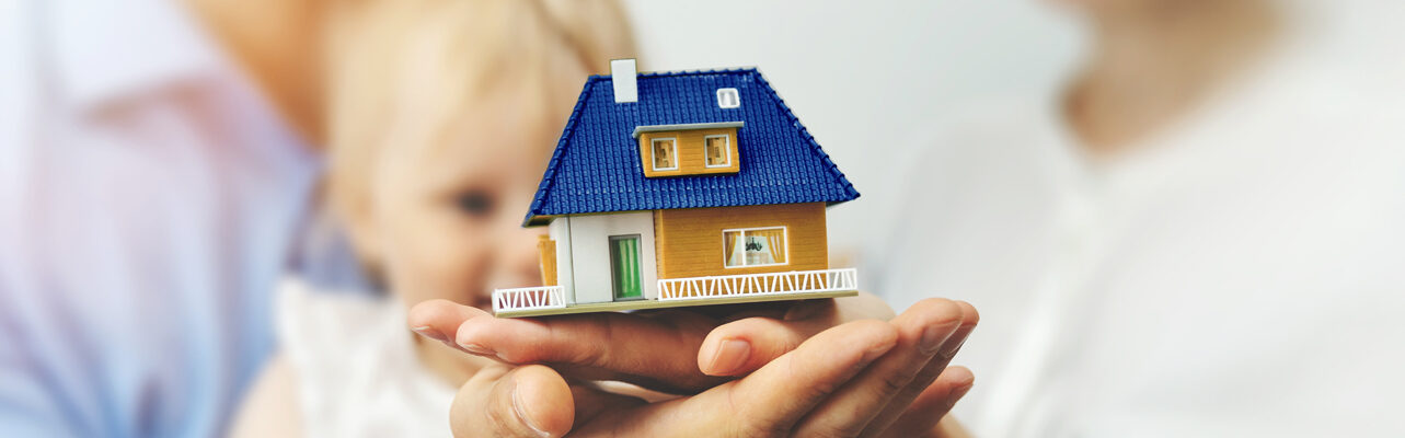 Familie hält Miniaturhaus auf Händen